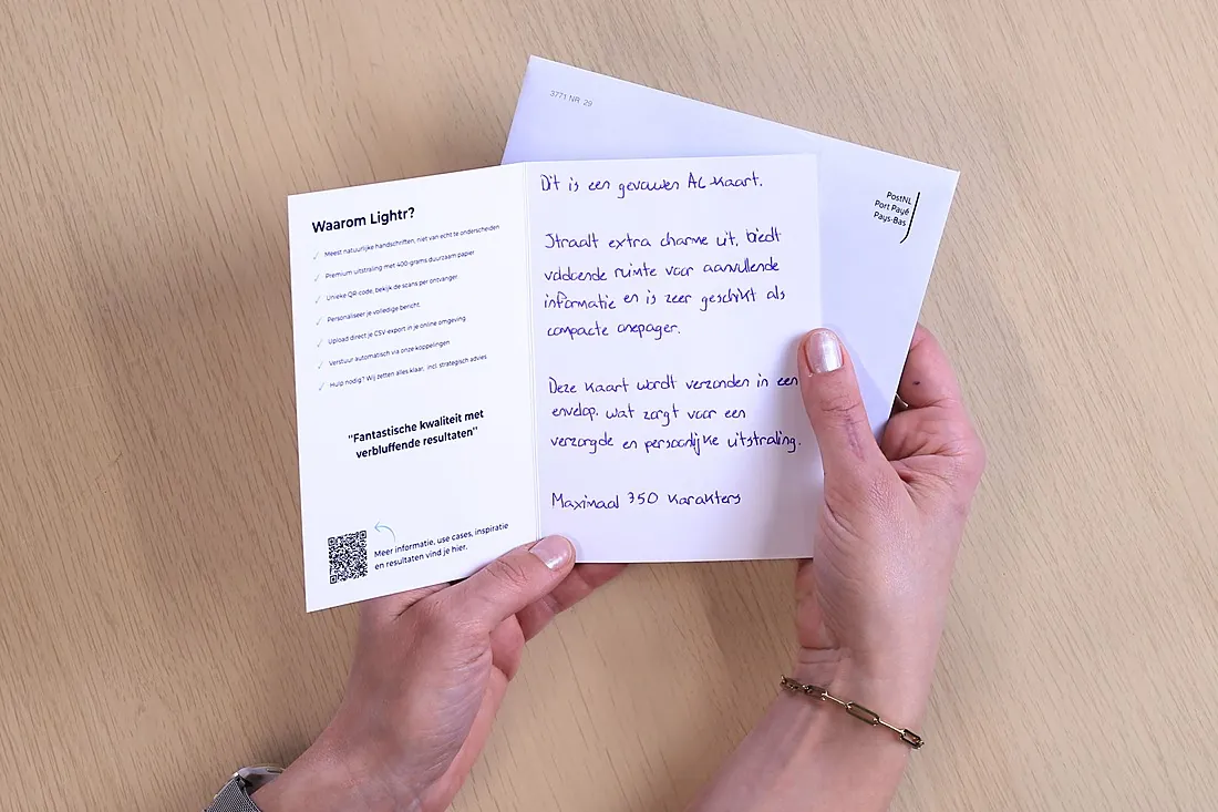 Opengevouwen A6-kaart met links gedrukte tekst en een QR-code, rechts met een echte pen geschreven