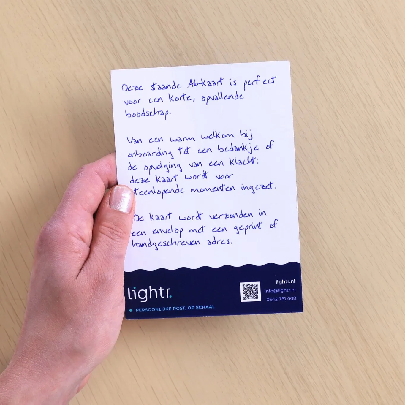 Staande A6-kaart, met een echte pen geschreven, met onderaan het Lightr-logo en een QR-code